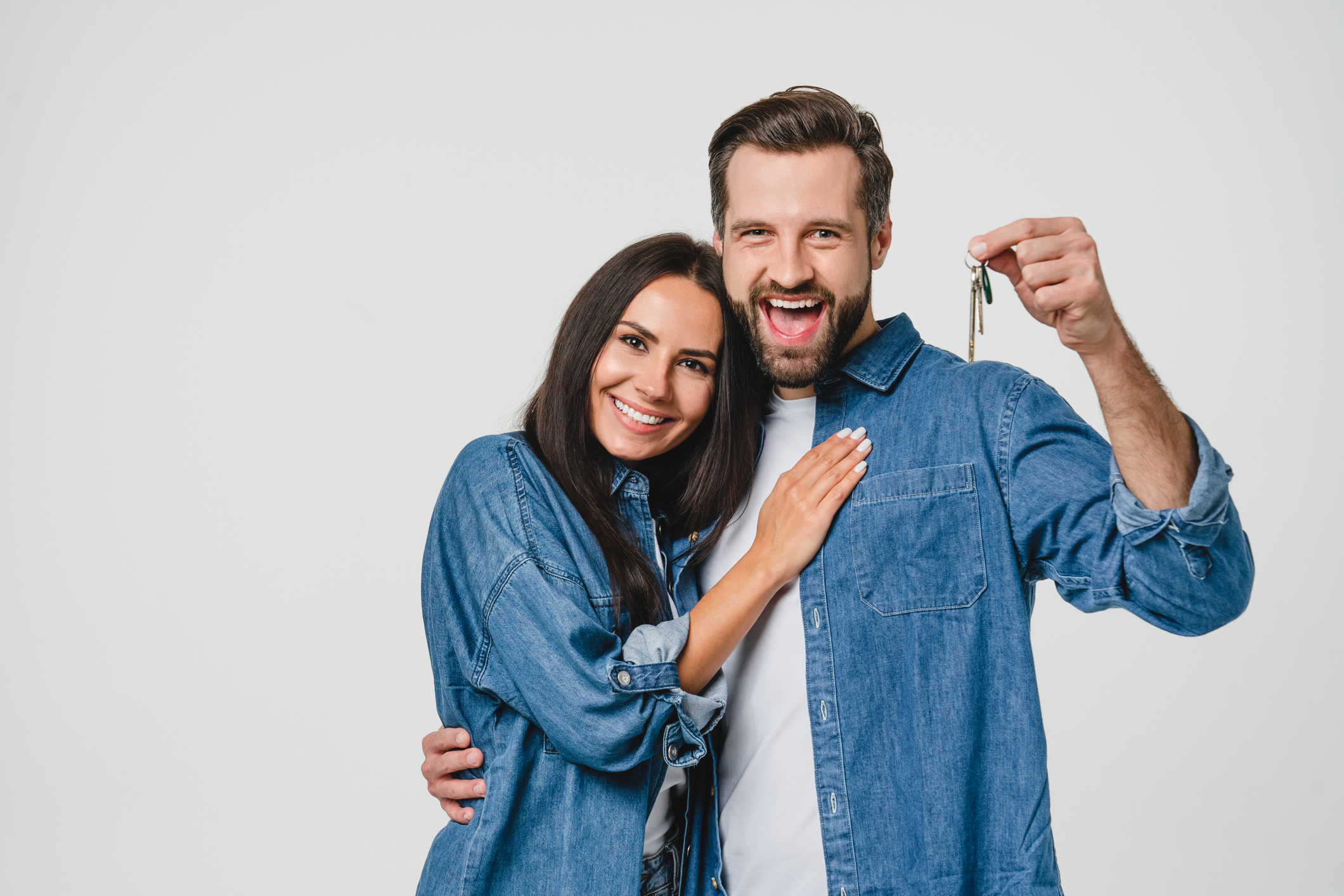 Homeowners. Happy young caucasian couple spouses wife and husband holding car house flat appartment keys, celebrating new purchase buying real estate isolated in white background.