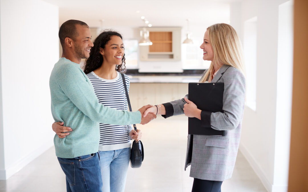 Female Real Estate Agent Shaking Hands With Couple Interested In Buying House