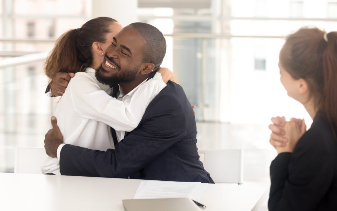 Happy diverse man and woman couple hugging for successful deal